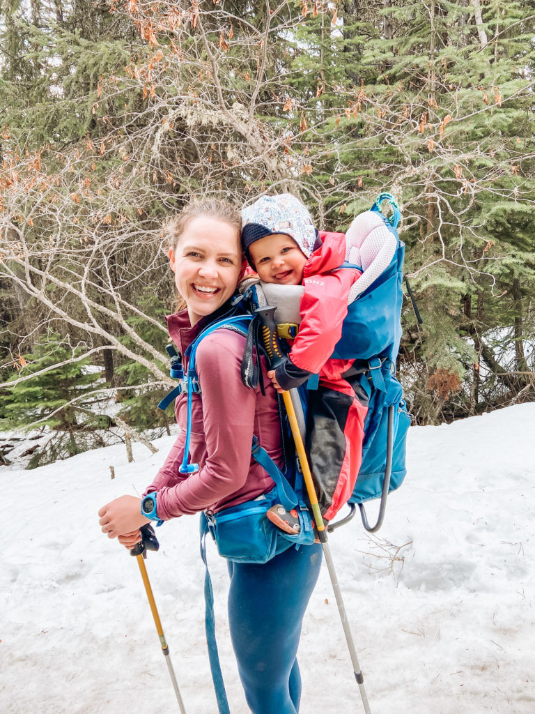 A young mom hikes in the snow with her daughter.