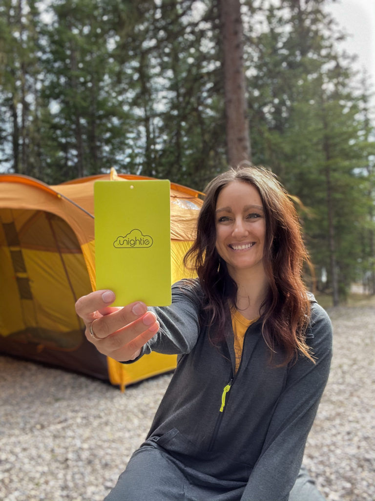 A woman holds up a Unightie for camping.
