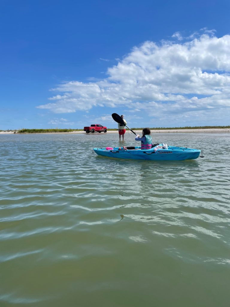 A family paddles along in shallow water.