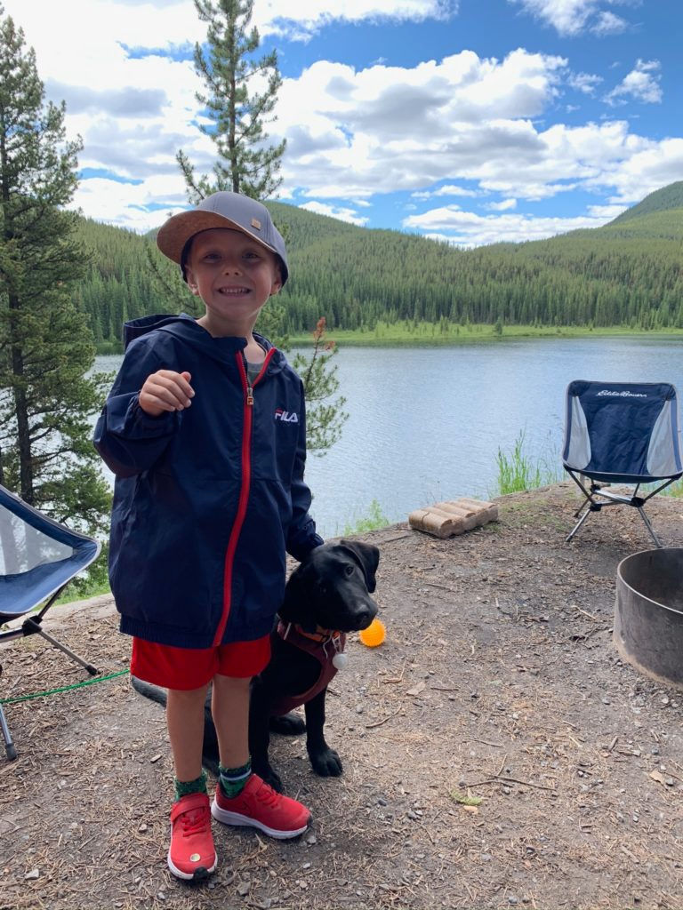 A young boy smiles while exploring a wilderness campsite.