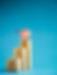 Target icon on top of wooden blocks with rise up arrows, 3d bar graph chart steps on blue