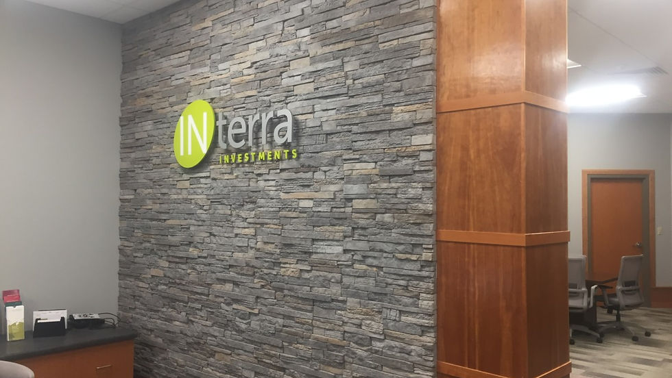 Tightly stacked stone in cool medium-gray tones with soft taupe accents creates a clean, professional look beside warm wood finishes.