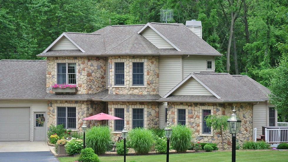 Rounded hand-split stones in warm tans, sandy beige, and soft browns with darker accents. A cozy cottage-style look beside landscaping.