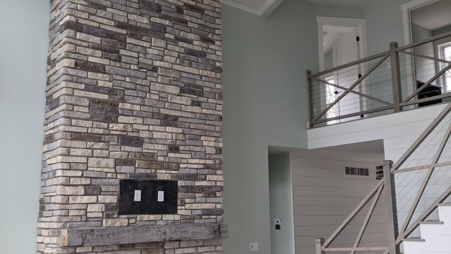 Linear stones in layered medium grays and soft taupes with deeper charcoal accents create a sleek, textured fireplace statement for interiors.