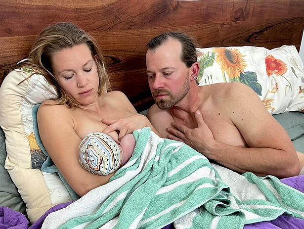 Austin mother breastfeeding her newborn after home birth with husband looking on