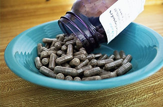 Placenta encapsulation capsules being poured into a bowl
