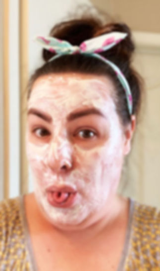 Vanessa, wearing a yellow shirt and a white, pink, and green hair strap tied in a bow, makes a funny face with facial cream all smeared all over