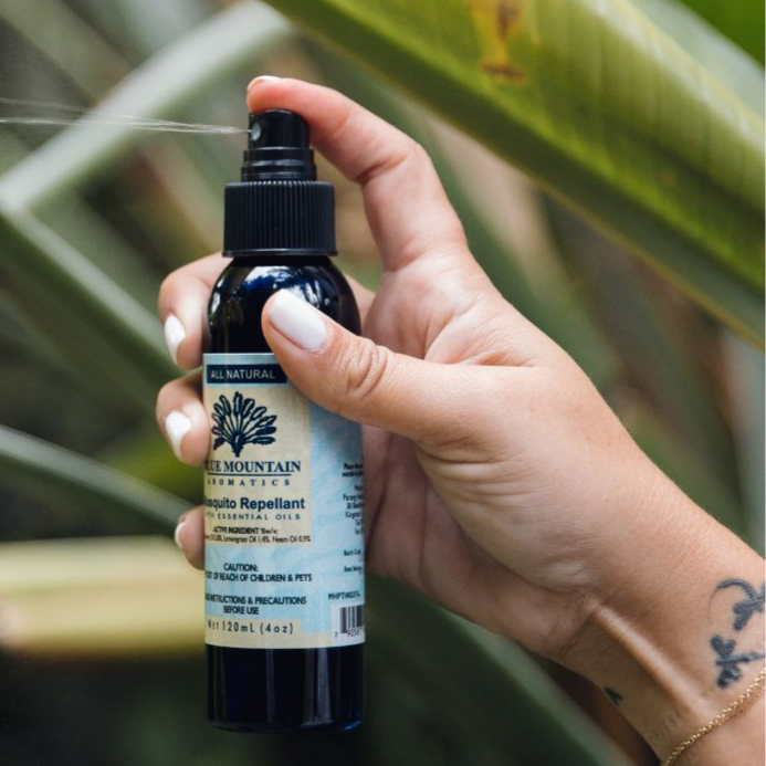 Hand holding a Blue Mountain mosquito repellent spray.