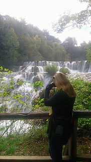 A woman photographs a waterfall