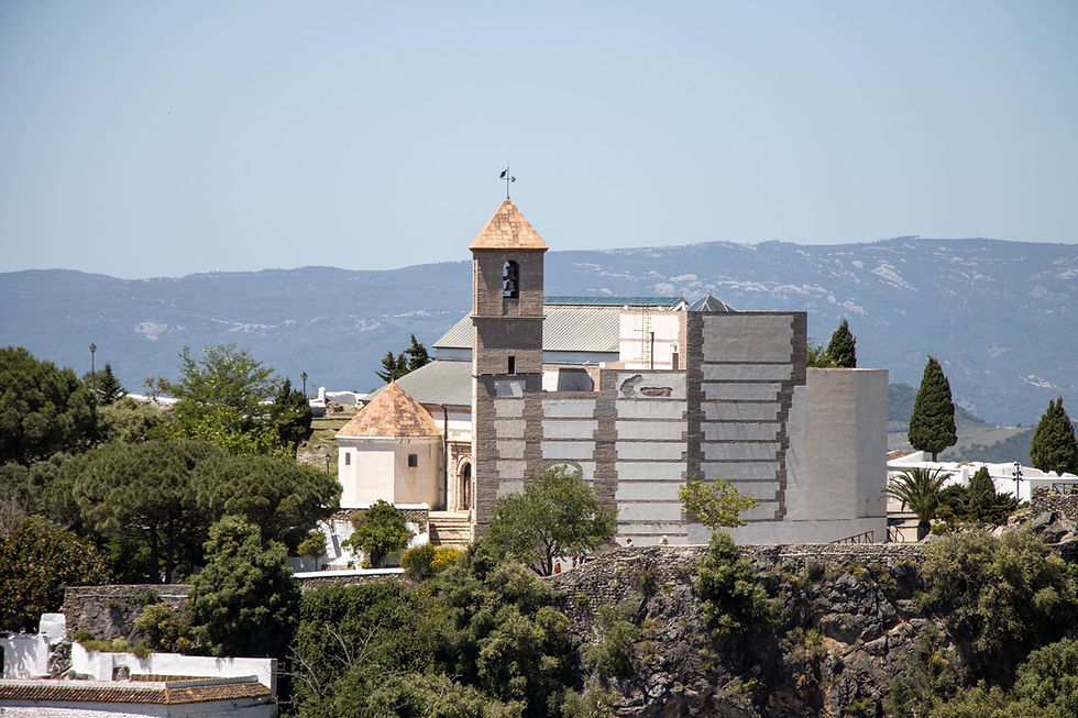 View of a historic church with a tower from a viewpoint in a white village.