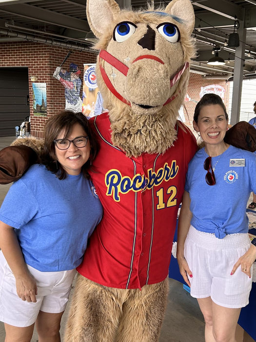 Two women with smiling camel mascot wearing a red jersey, 