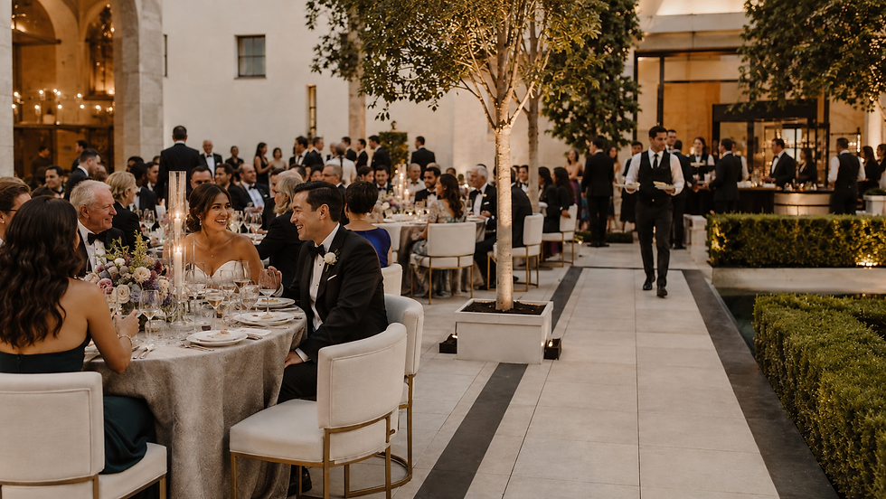 Newlyweds and guests enjoying dinner while wedding service and reception logistics continue in the background.