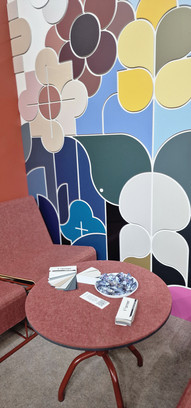 Rode fauteuil en tafel met kleurstalen bij kleurrijke abstracte muurschildering.