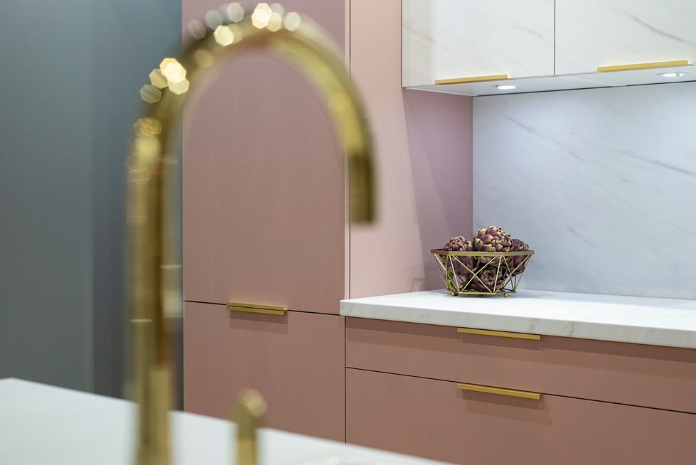 Moderne roze keuken met gouden kraan en marmeren aanrechtblad.