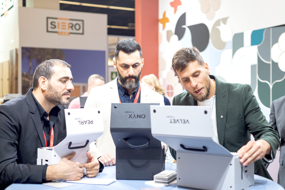 Drie mannen bestuderen PEARL, ONYX, VELVET materialen bij SIERO GROUP stand.