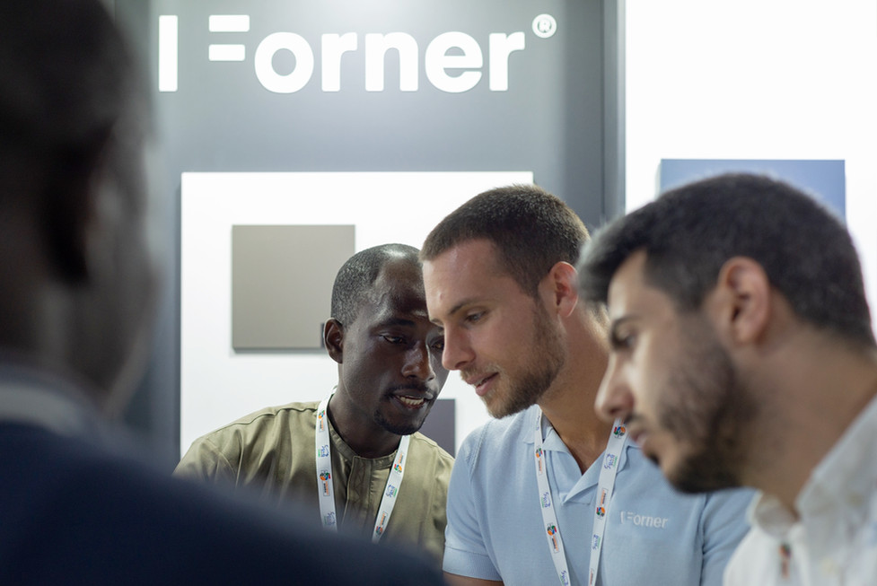 Drie mannen bekijken productstalen bij I Forner stand.