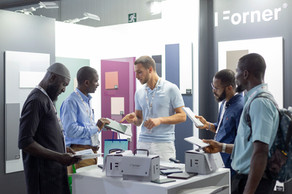 Mannen bespreken Forner materialen en samples op een beursstand.