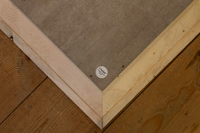 Achterkant houten lijst hoek met Fischer sticker op houten vloer.