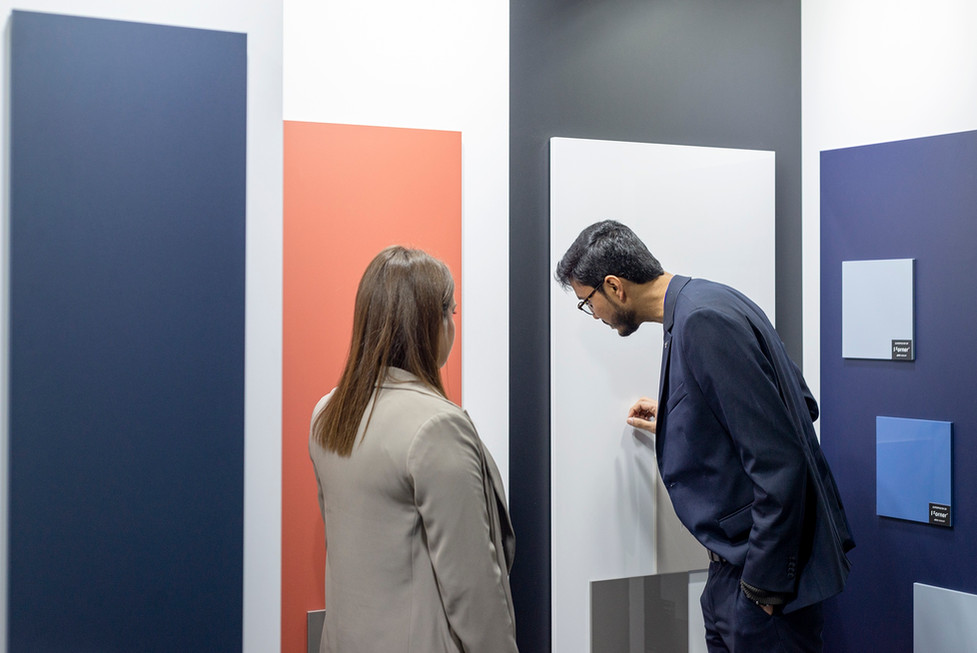 Twee bezoekers inspecteren verschillende gekleurde panelen op een beurs.