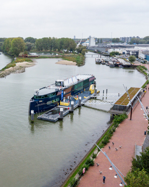 Lange donkerblauwe boot aangemeerd aan een moderne drijvende pier.