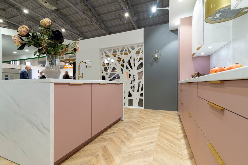Moderne roze keuken met eiland, houten vloer en decoratieve scheidingswand.