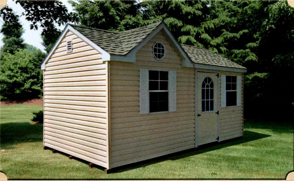 10x16 Quality Vinyl Cottage with dormer style, tan siding, white trim, architectural shingle roof, double-hung window, arched transom window, decorative oval gable window, and gable vent, displayed on grass with natural backdrop