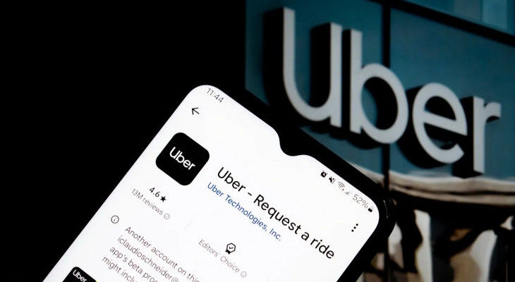 Phone screen displaying the Uber app details; background shows large Uber sign on building, creating a modern tech vibe.