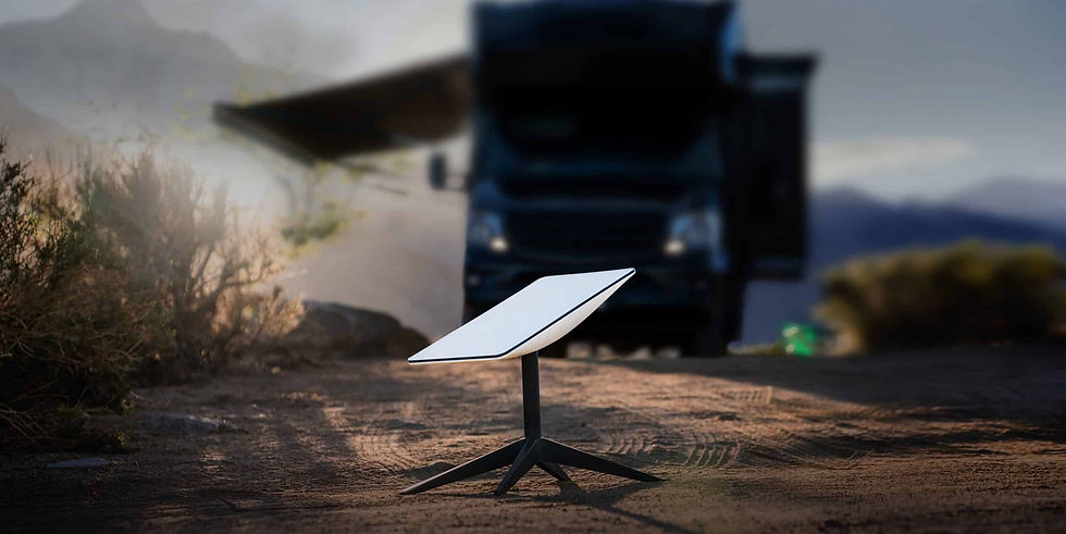A Starlink dish on dirt foreground, blurry RV in background. Desert setting with soft, natural light and dry plants around.