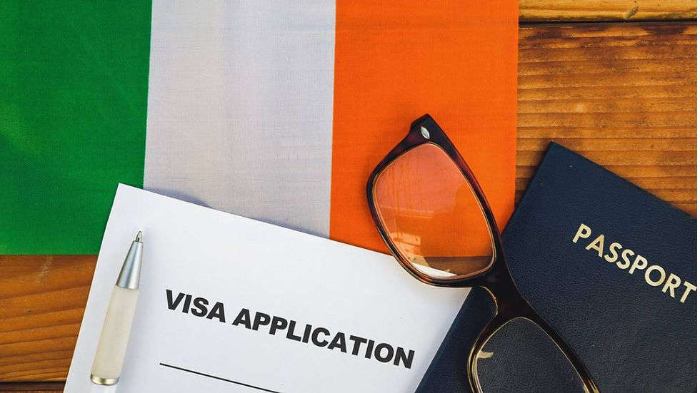 Visa application and pen on wooden table with Irish flag. Glasses and passport beside, creating a formal travel-related setting.