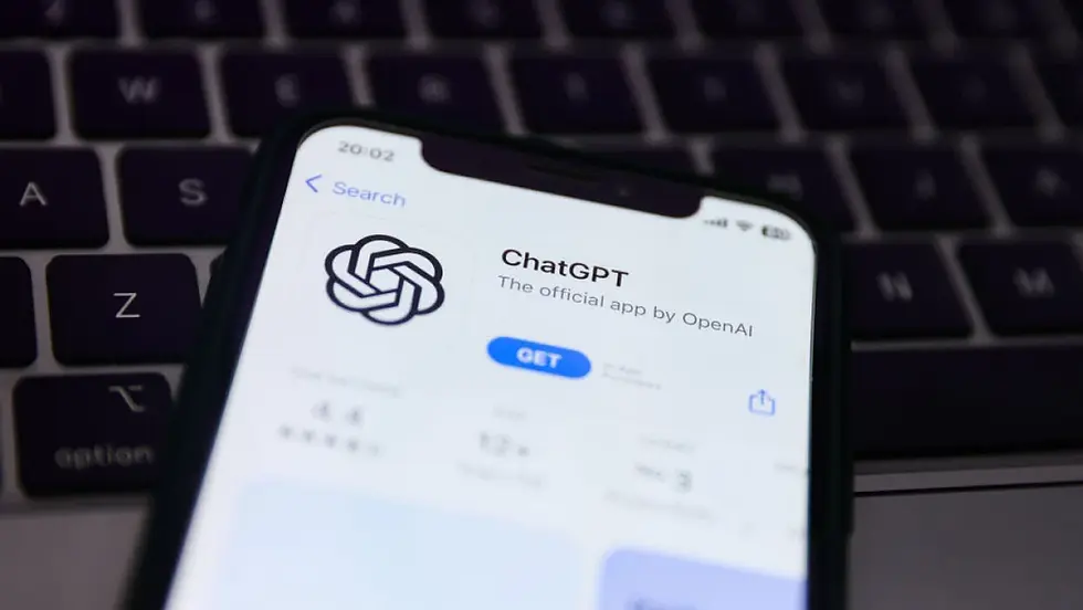 Close-up of a phone displaying the ChatGPT app on a dark keyboard. The app, open on the App Store, shows a "GET" button.