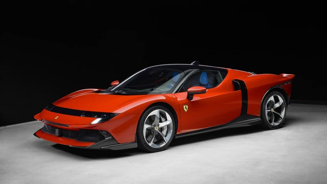 Sleek red sports car parked on a concrete floor against a black background. Features sharp lines and a prominent badge on the side.
