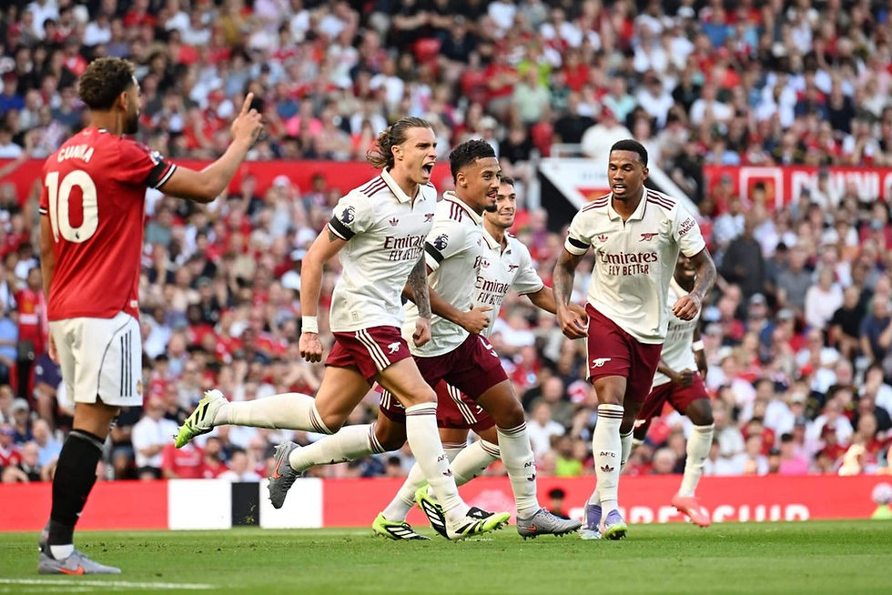 Soccer players in white and maroon jerseys celebrate energetically on the field. A red-clad player stands nearby. Crowd in the background.