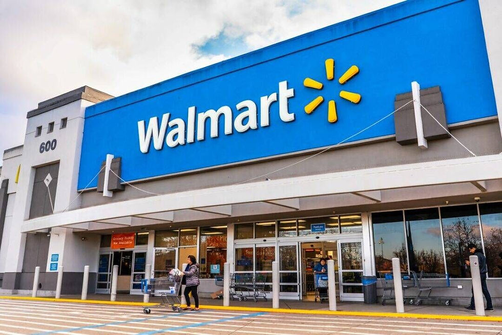 A woman pushes a cart outside a Walmart store with a blue sign. The building is gray and white with a visible number 600. Sky above.