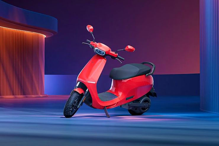 Red scooter on smooth purple-blue floor, sleek design. Neon-lit futuristic backdrop with curved structures, creating a modern, vibrant mood.