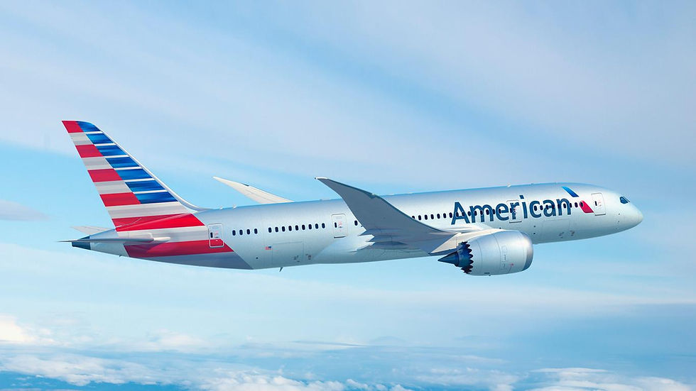 Silver airplane with red and blue stripes, marked "American," flies through a clear, blue sky. The mood is calm and serene.