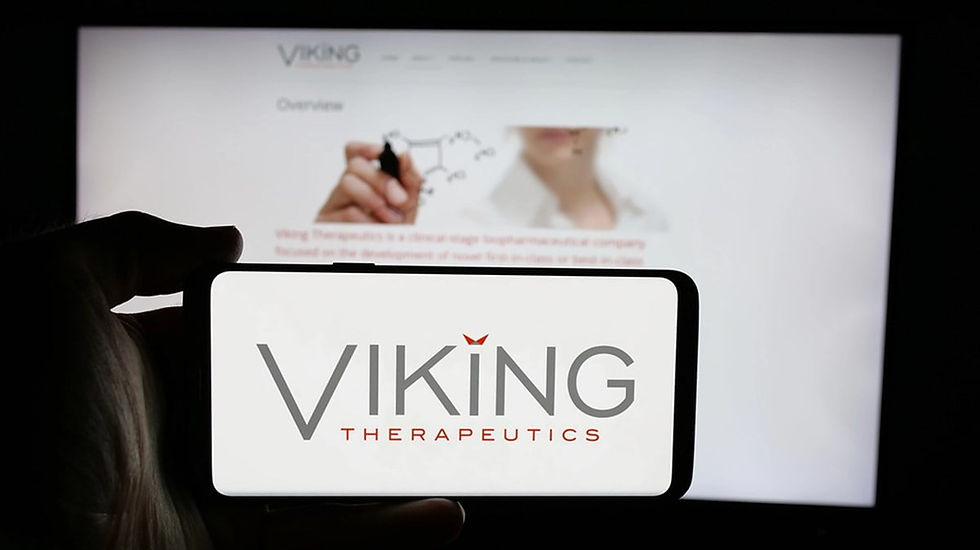 Phone screen displays "Viking Therapeutics" logo. Background shows blurred website with hand drawing a chemical structure. Dark setting.