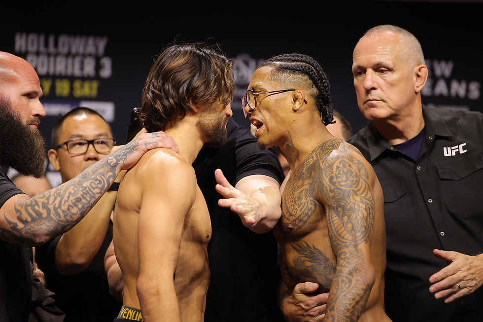Two shirtless fighters face off at a UFC event. One is speaking intensely, while staff intervene. Visible tattoos and intense expressions.