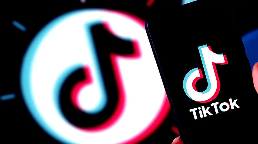 Close-up of a smartphone displaying the TikTok logo, with a blurred, larger TikTok logo in the background. Colors are black, white, and neon.