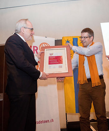 Der ehemalige Gemeindepräsident Martin Laupper (links) nimmt die Auszeichnung als erste Fair Trade Town der Schweiz für Glarus Nord entgegen.