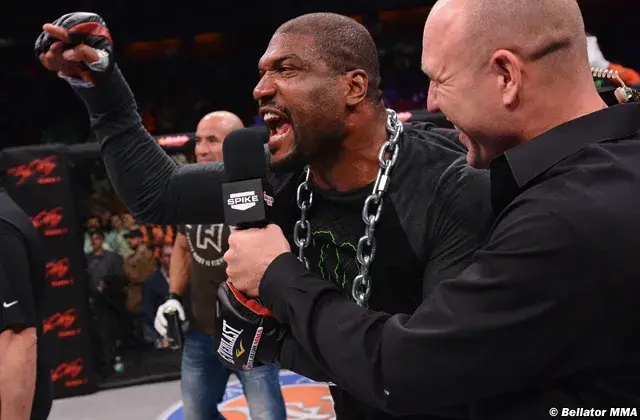MMA fighter with a chain, shouting excitedly in a ring while holding a microphone. People cheer in the dim arena. Text: Spike and Bellator MMA.