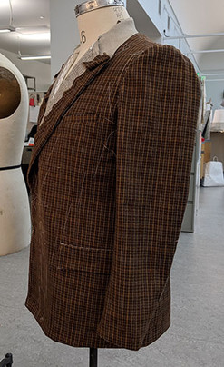 Wool Plaid Jacket Side Front work in progress for San Francisco Opera's Orlando. A brown wool plaid jacket with white basting holding canvas in place. Pocket flaps and sleeves basted on. 