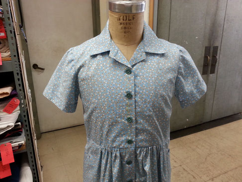 Child's Shirt Dress for San Francisco Opera's Two Women. A blue cotton shirt dress with white polka dots, convertible collar, and buttons down the front. 