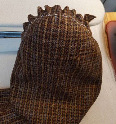 Wool Plaid Jacket Sleeve work in progress for San Francisco Opera's Orlando. A brown wool plaid jacket sleeve, with hand easing stitches, steamed over a ham. 