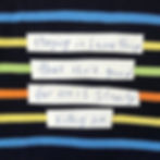 Cut up strips of paper with the following words on them handwritten in black sharpie marker, on black fabric with multi colour thick lines: "Staying in something that isn’t good for me is slowly killing me”
