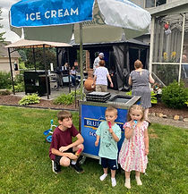 Kids enjoying ice cream while standing in front of an ice cream cart rental from double bounce party rentals in Washington Twp, Michigan