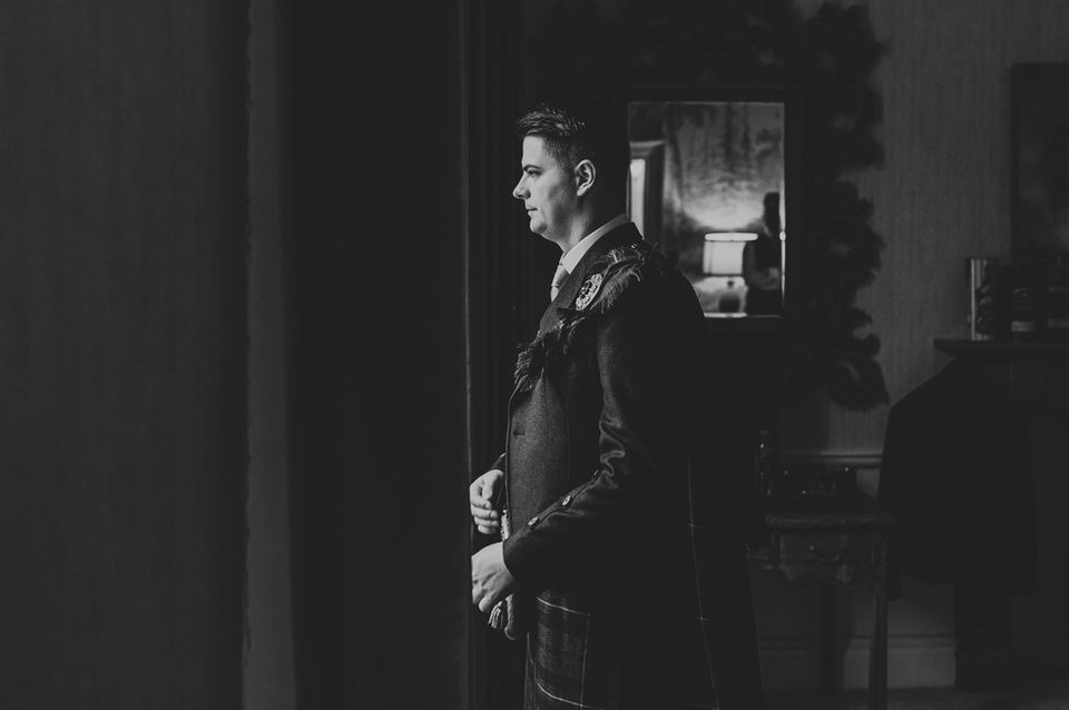 Groom standing in spotlight holding a microphone at Balbirnie House captured by Karol Makula Photography.