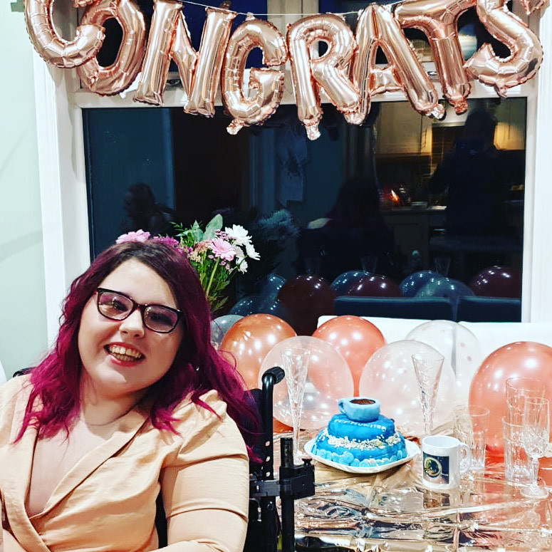 Hannah Pierce at Communitea Launch Party sitting in front of teacup cake with lots of balloons