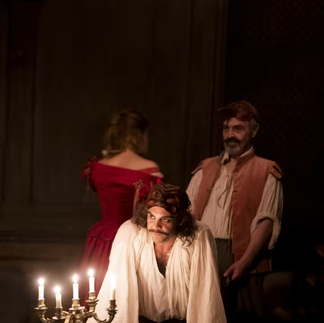 Photo de scène éclairée à la bougie, montrant un acteur déguisé en Molière, réfléchissant profondément, soulignant la mise en scène intime et historique de Julie Deliquet.