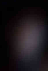 Un acteur masculin semble réfléchir profondément sur scène, éclairé par les projecteurs, suggérant une scène théâtrale intime et poignante.