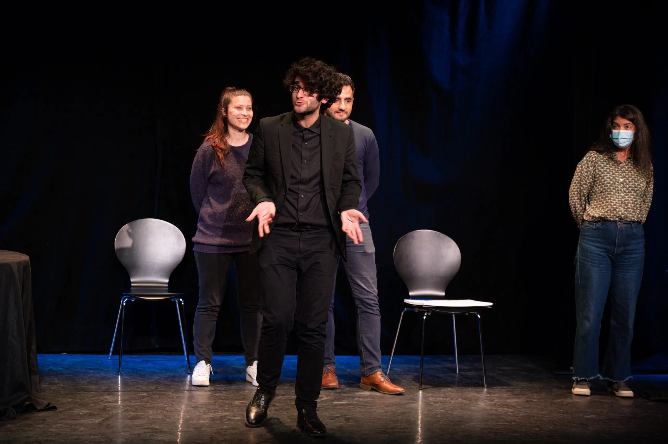 Taha Mansour sur scène avec deux volontaires, visiblement dans un moment interactif de son spectacle. Ils sont souriants, suggérant un moment agréable et divertissant.